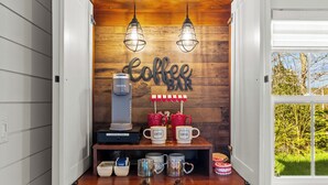 Um café com máquina de café, canecas e um letreiro que diz 'Coffee Bar'.