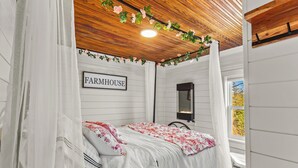 Quarto com cama, mesa de cabeceira, espelho e janela.