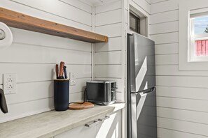 Una cocina con un refrigerador de acero inoxidable, un tostador y una tabla de cortar de madera sobre la encimera.