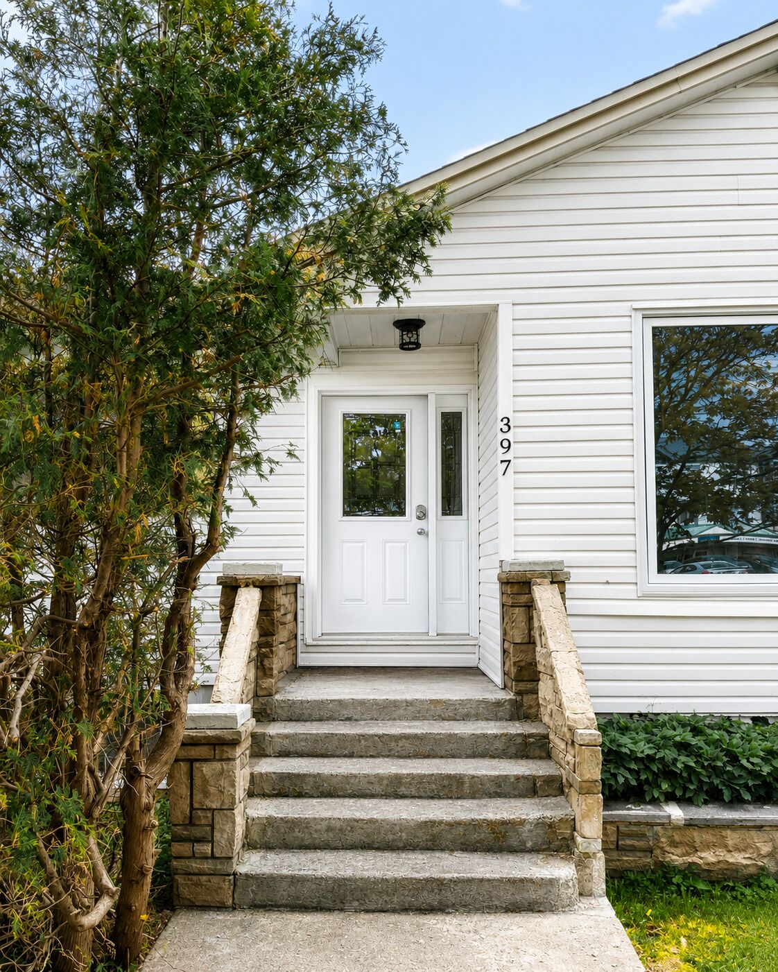 A white house with a stone staircase leading to a white door marked with the number 397.