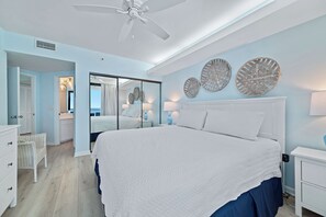 A bedroom with a large bed, a ceiling fan, and a view of the ocean through a sliding door. - Beachfront Corner Views, Indoor & Outdoor Pools, Walk to Dining | BEACHBALL PROPERTIES (Orange Beach)
