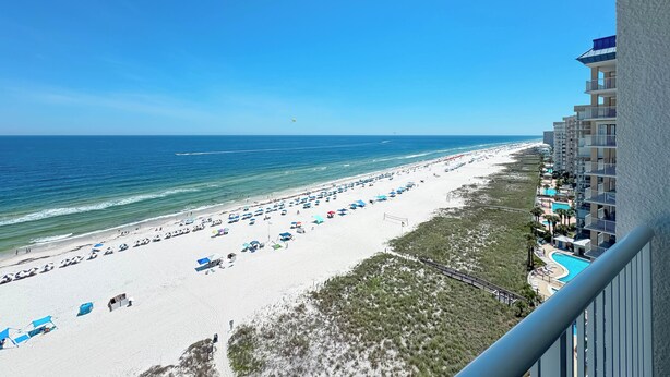 A beach view with a hotel, clear skies, and a distant ship. - Beachfront Corner Views, Indoor & Outdoor Pools, Walk to Dining | BEACHBALL PROPERTIES (Orange Beach)