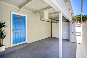 Eine Garage mit blauer Tür, einer weißen Garagentür und einem Betonboden.