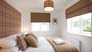 Une chambre à coucher avec un lit, une fenêtre donnant sur un paysage agréable, un radiateur et un luminaire fixé au mur.