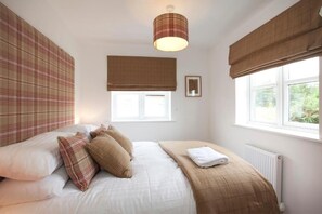 A bedroom with a bed, a window with a view, a radiator, and a wall-mounted light fixture.