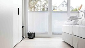 Una habitación moderna con una puerta de cristal corredera, un sofá blanco y una cesta trenzada negra en el suelo.