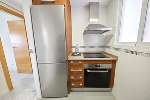 Una cocina compacta con refrigerador de acero inoxidable, horno integrado y microondas.