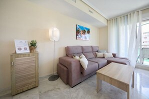 A modern living room with a sofa, a coffee table, a lamp, a cabinet, and a painting on the wall. - VILA PARK relax apartment (La Vila Joiosa)