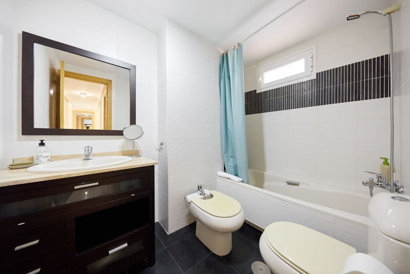 Une salle de bain équipée d’un lavabo, d’un miroir, de toilettes et d’une baignoire.