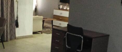 Een hotelkamer met een bed, een bureau, een stoel, een televisie en een kleine kitchenette.