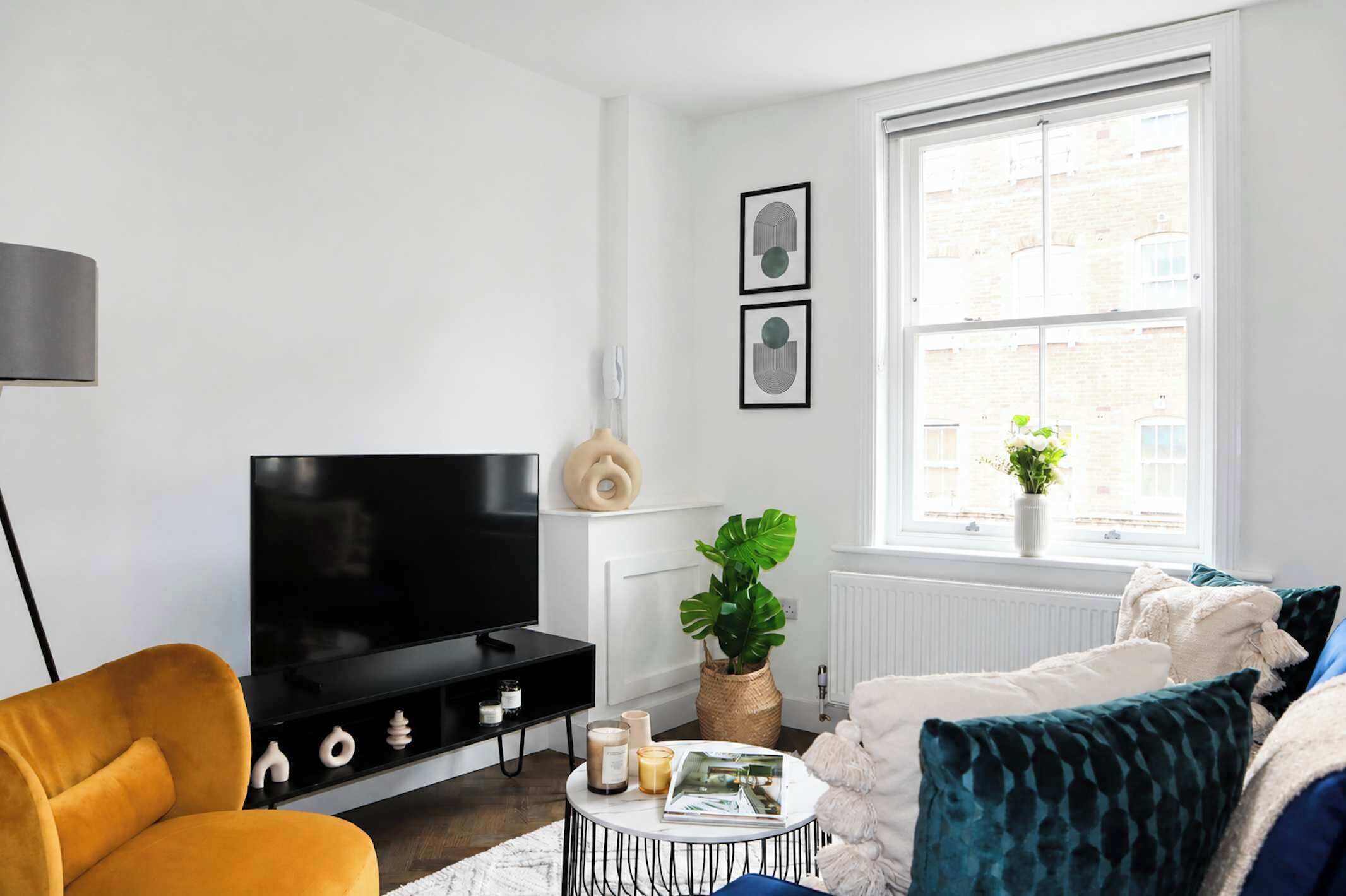 A living room with a TV, sofa, coffee table, and a window with a view.