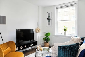 Ein Wohnzimmer mit Fernseher, Sofa, Couchtisch und einem Fenster mit Blick.