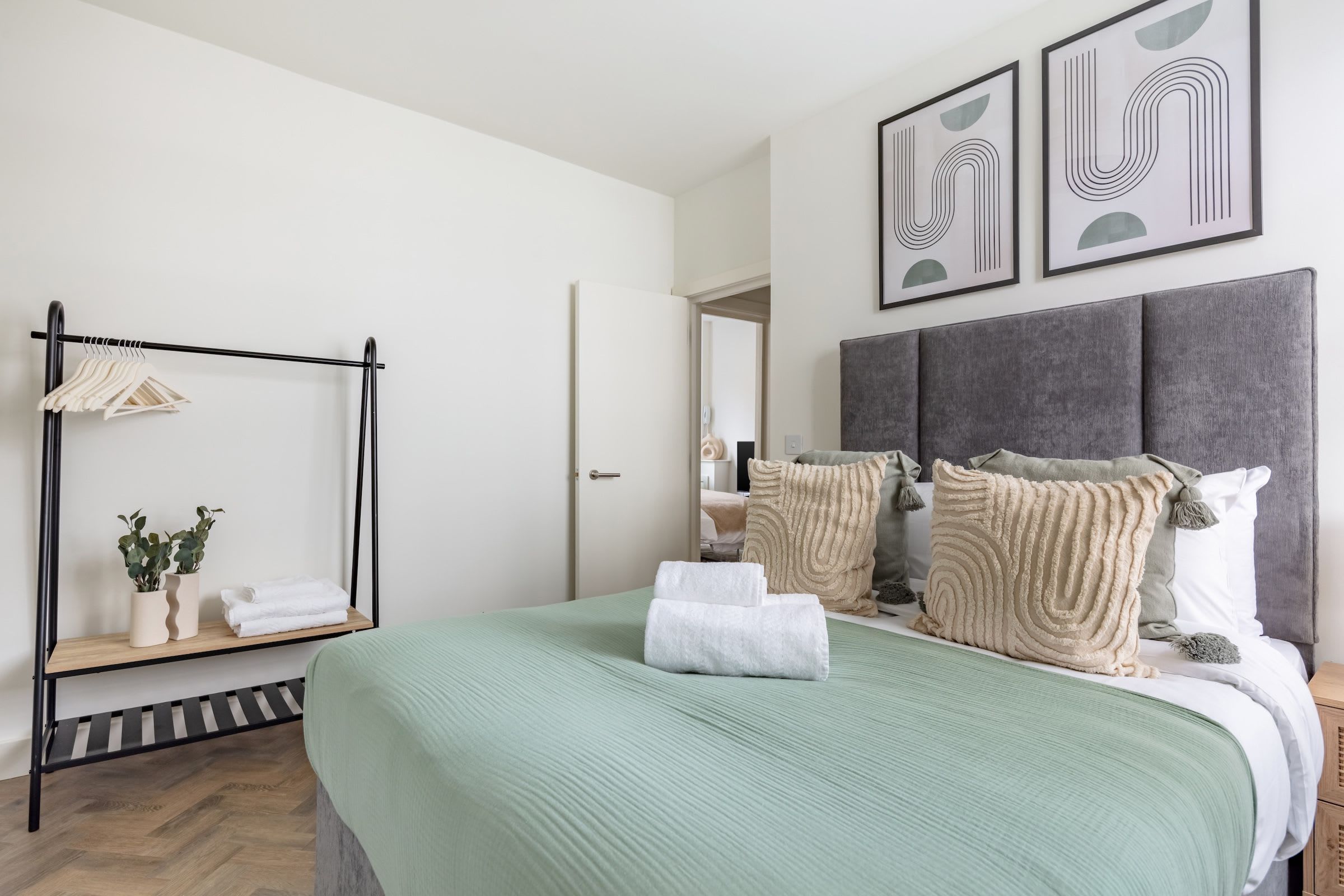 A modern bedroom with a bed, a hanging wardrobe, and a mirror.