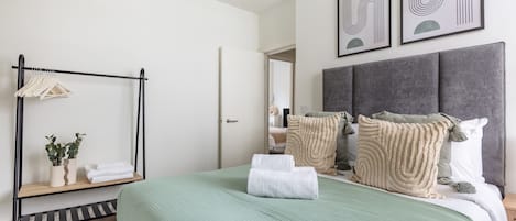 A modern bedroom with a bed, a hanging wardrobe, and a mirror.