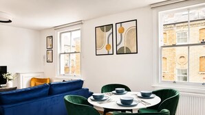 Un coin repas avec une table ronde, des chaises vertes et des bols bleus.