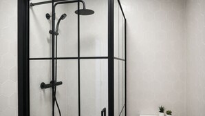 Une cabine de douche dotée d’un cadre noir, d’un pommeau de douche à main, d’un pommeau de douche fixe et d’un accessoire de douche à main.