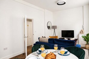 Ein modernes Wohnzimmer mit Sofa, Fernseher und Essbereich mit Frühstück.