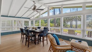A conservatory with a dining table, chairs, and a ceiling fan.