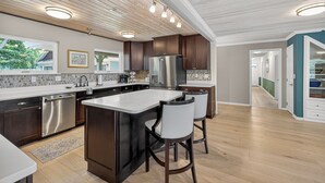 A modern kitchen with a central island, stainless steel appliances, and a view to the outside.