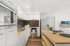 Eine moderne Küche mit Edelstahlgeräten, weißen Schränken und einer Holz Arbeitsplatte.
