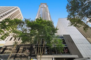 A modern building with a glass facade, surrounded by trees. - Urban Retreat 1Bed-1Bath-Study-Balcony-1Car (Brisbane City)