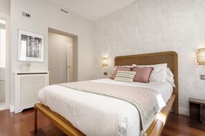 A bedroom with a large bed, a bedside table, a wall-mounted light, and a framed picture. - Stylish 4BD Apartment Madrid Duque de Osuna II (Madrid)