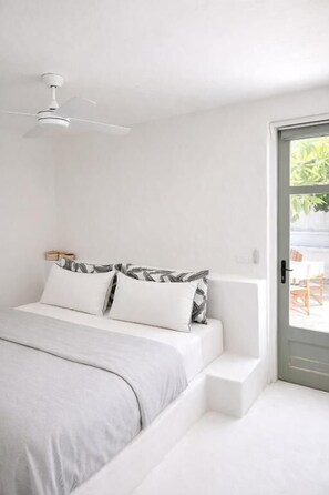 A bedroom with a bed, a ceiling fan, a door, and a view of the outdoors. - My Island Home Vanuatu (Eton)