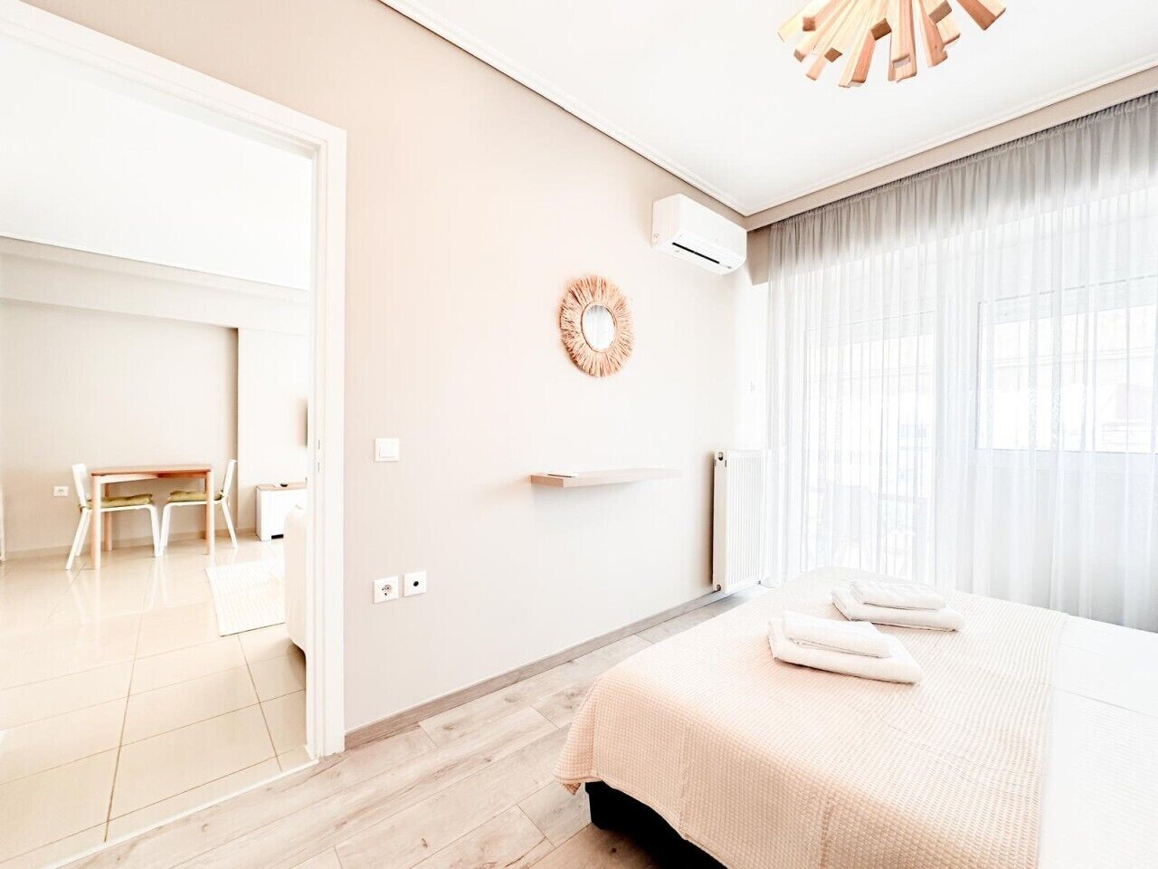 Una habitación de hotel moderna con cama, una mesita, una silla, un espejo y un radiador.