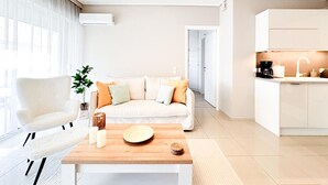 A modern living room with a sofa, a coffee table, and a pendant light. - Bright Modern 1BR · 4-min Walk to the Sea · Alimos Riviera (Alimos)
