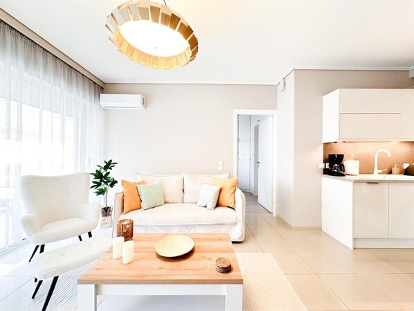 A modern living room with a sofa, a coffee table, and a pendant light. - Bright Modern 1BR · 4-min Walk to the Sea · Alimos Riviera (Alimos)