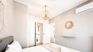 A hotel room with a bed, a bedside table, a wall-mounted air conditioner, and a decorative wall piece. - Bright Modern 1BR · 4-min Walk to the Sea · Alimos Riviera (Alimos)