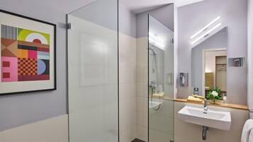 A modern bathroom with a glass shower enclosure, a white sink, and a mirror.