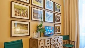 A hotel room with a wooden floor, a bed, two green chairs, a wooden cabinet with alphabet letters, and framed pictures on the wall. - Hotel 38  (Berlin)