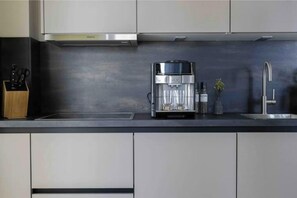 A modern kitchen with a built-in coffee maker, a knife block, and a sink. - Sunseeker - Sankt Peter-Ording Vacation Rental for 2 People (Sankt Peter-Ording)