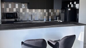 Een moderne keuken met zwarte kastjes, een zwart aanrecht en een ingebouwd fornuis.
