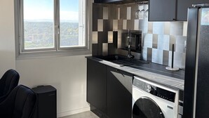 Een moderne keuken met een groot raam, een ingebouwde wasmachine en een zwart aanrecht.