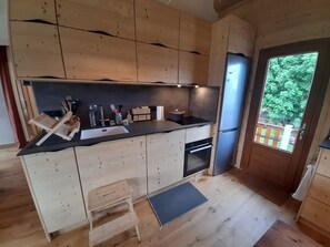 Eine moderne Küche mit Holzschränken, einer schwarzen Arbeitsplatte, einem Spülbecken, einem Herd und einem Kühlschrank.
