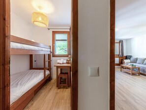 A bunk bed room with a window, a small table with towels, and a wooden floor. - Apartment mountain view - 4 guests (Val-d'Isère)