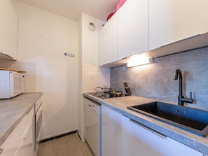 A modern kitchen with white cabinets, a grey countertop, a built-in dishwasher, and a black sink. - Apartment mountain view - 4 guests (Val-d'Isère)