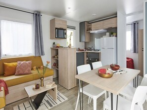 Ein kompakter Wohnbereich mit Sofa, Esstisch, Küchenzeile und einer kleinen Küchennische.