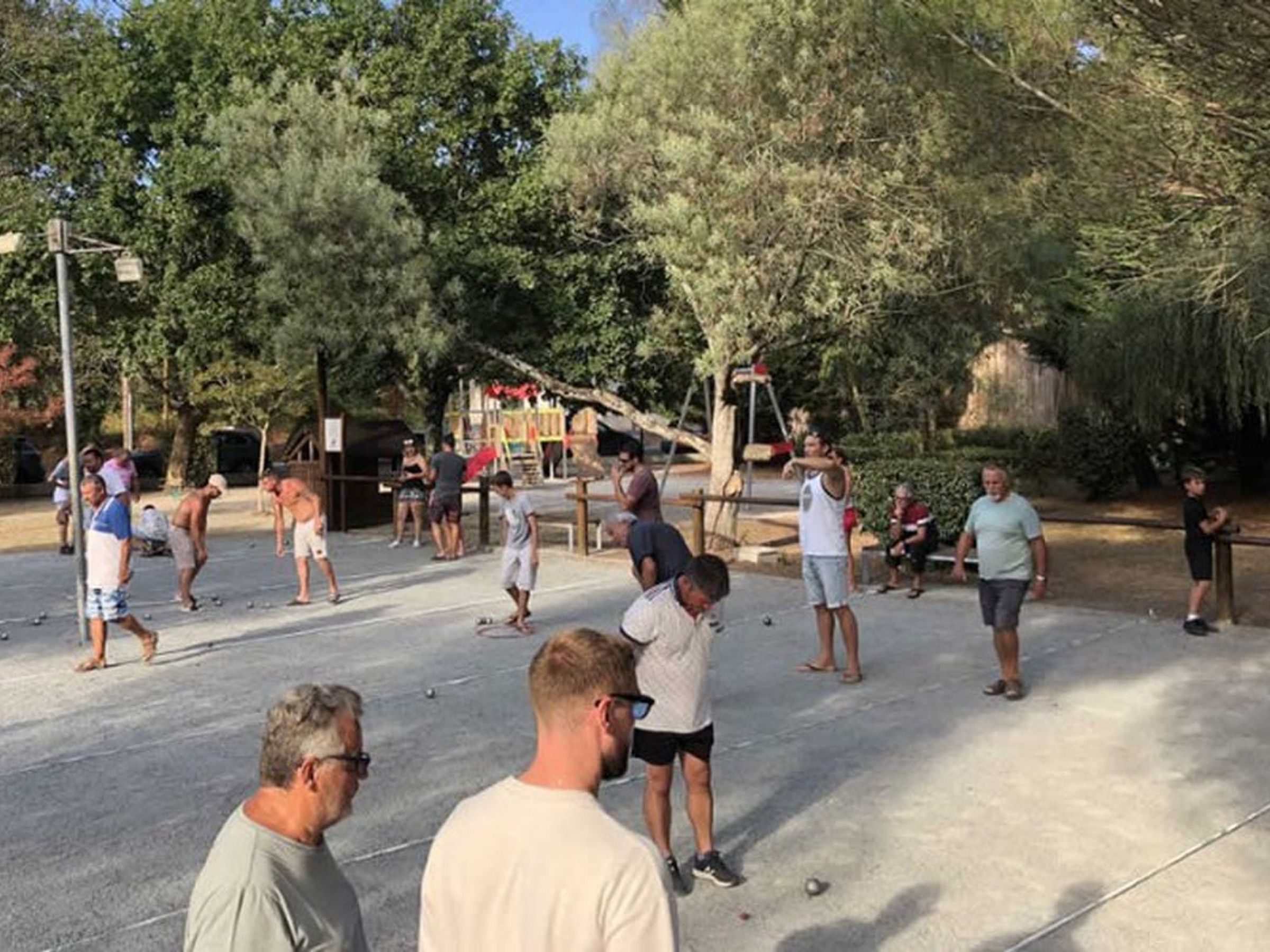 Un gruppo di persone che gioca all'aperto, con alberi e un'area giochi sullo sfondo.