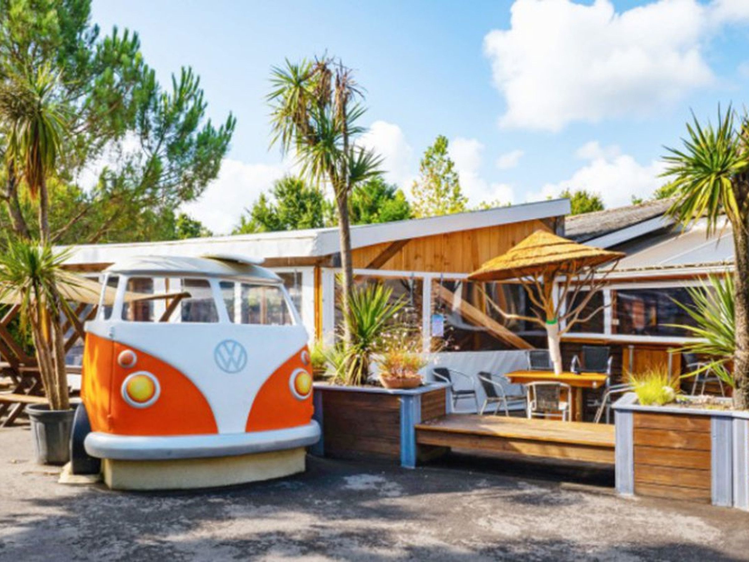 A VW bus converted into a restaurant with outdoor seating and a wooden deck.