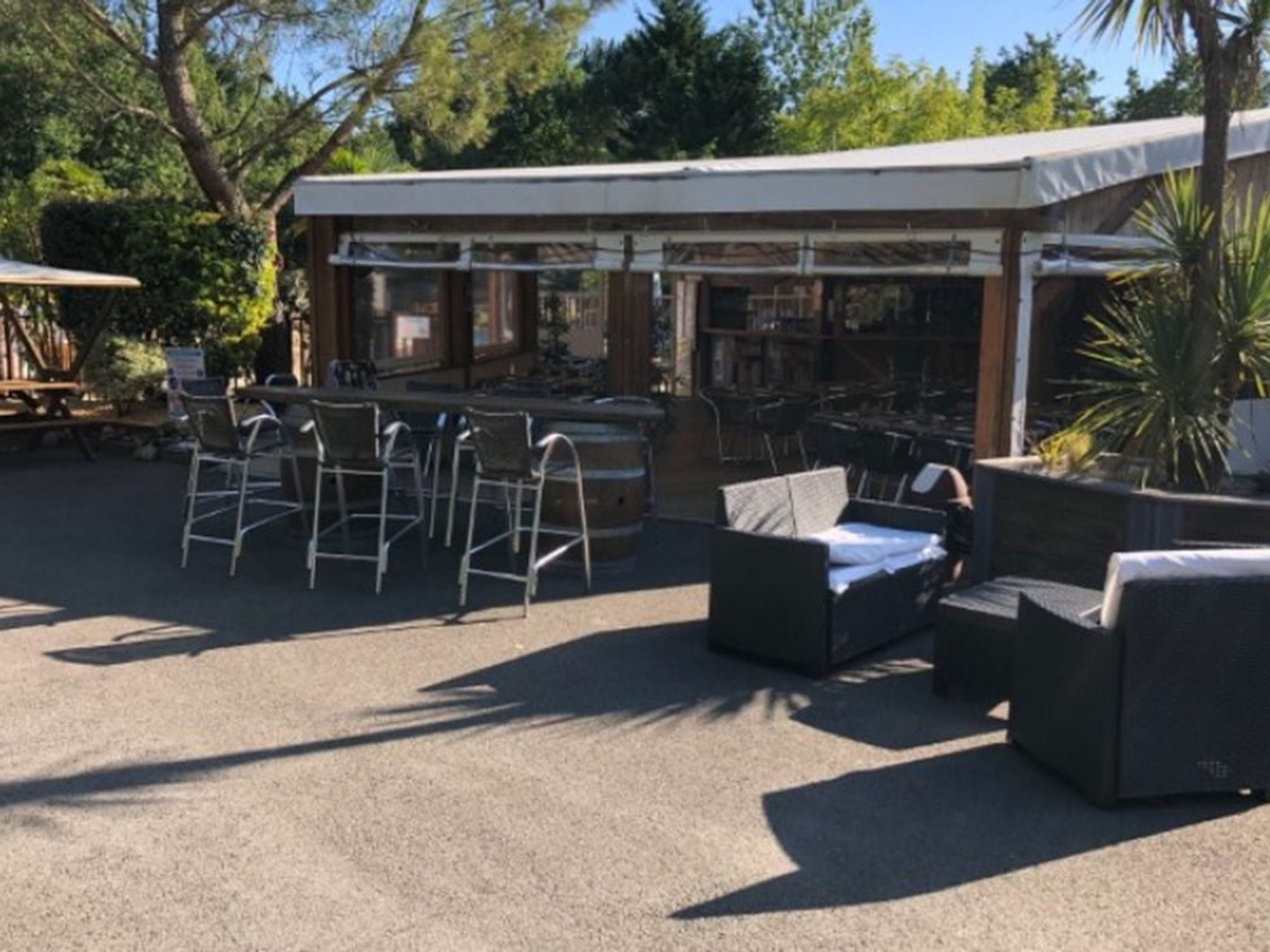 Un espace extérieur aménagé avec des tables et des chaises, une terrasse couverte et une piscine.