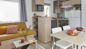 Ein gemütlicher Wohnraum mit Sofa, Esstisch, Küchenzeile und Mikrowelle.