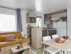 Ein gemütlicher Wohnraum mit Sofa, Esstisch, Küchenzeile und Mikrowelle.
