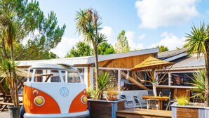 Ein umgebauter VW-Bus, der als Restaurant mit Außenbestuhlung und einer Holzterrasse dient.