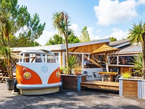 Ein umgebauter VW-Bus, der als Restaurant mit Außenbestuhlung und einer Holzterrasse dient.