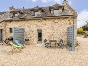 A stone building with a gravel driveway, a table with chairs, and a hammock. - Charming cottage in Clis - 2 guests (Guérande)