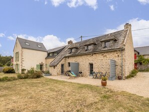 Ein Steinhaus mit Satteldach, einem kleinen Garten mit Schaukel und einer Schotterzufahrt.