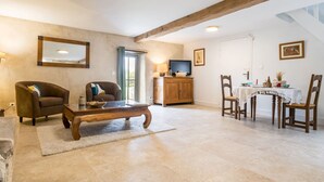 A spacious living area with a wooden coffee table, two armchairs, a television, and a dining table with chairs. - Charming cottage in Clis - 2 guests (Guérande)